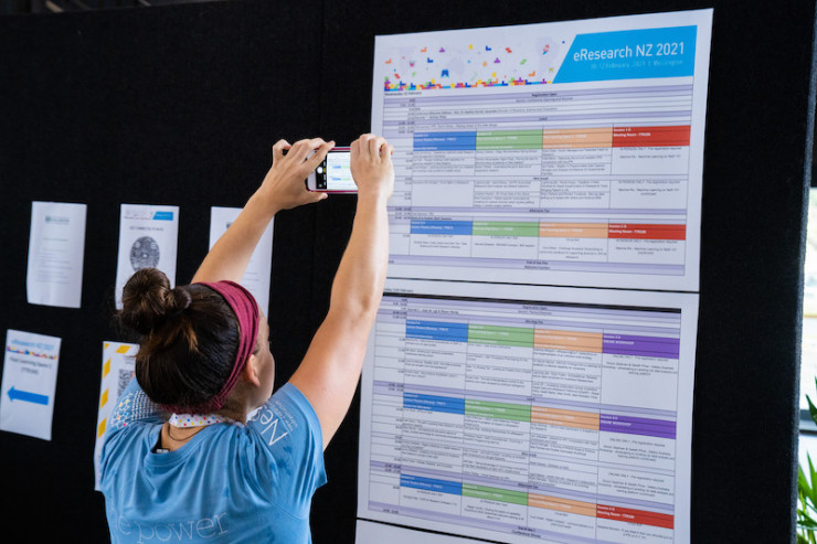 Person taking photo of the conference programme display board