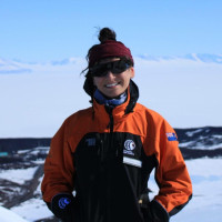 Picture of Alanna standing on an ice sheet wearing a parka and sunglasses.